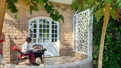 a woman sitting at a table in front of a door at Dream Garden Luxor in Luxor