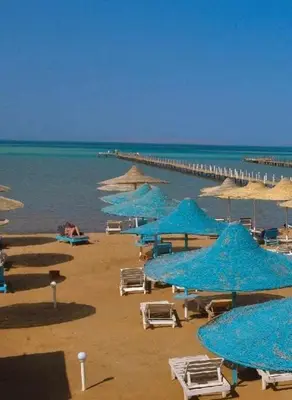 a group of blue umbrellas and chairs on a beach at Fox Resort El Gouna in Hurghada