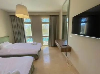 a bedroom with two beds and a flat screen tv at Stunning 2 BR/ Free Beach & Pool Access @ Mangroovy, El Gouna in Hurghada