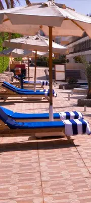 two lounge chairs and an umbrella on a patio at Fox House Beach Resort & Spa El Gouna in Hurghada