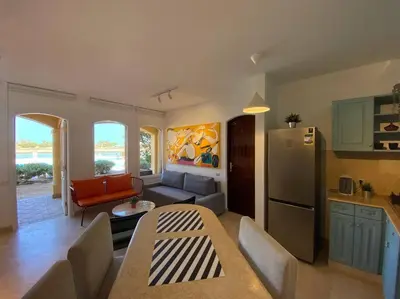 a kitchen and living room with a table and a refrigerator at Magical 2BR Ground/Free Pool & Lagoon Access @ElGouna in Hurghada