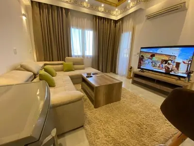 a living room with a couch and a flat screen tv at Makadi heights luxury apartment in Hurghada
