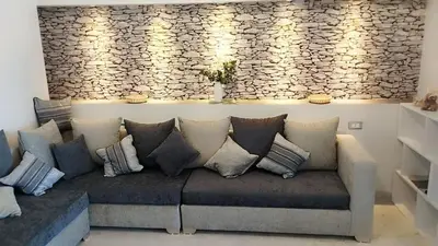 a couch in a living room with a stone wall at Evi's Infinity Sea View Apartment in Hurghada
