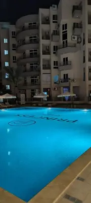a large blue swimming pool in front of a building at Velký apartmán Princess Resort Hurghada in Hurghada