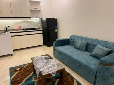 a living room with a blue couch and a kitchen at Mirage bay in Hurghada