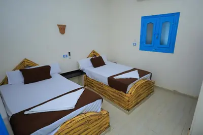 a room with two beds and a blue door at Nubian Popeye - Roof top - Nile View in Aswan