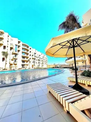 a swimming pool with a bench and an umbrella at Hotel Room in Princess Resort With Beach Acces & Free Wi-fi I Near Air port in Hurghada