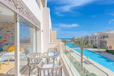 a balcony with a table and chairs and a pool at Beach-Inspired 1BR in Mangroovy, El Gouna. Sea & Pool in Hurghada