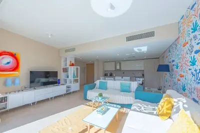 a living room with a blue couch and a kitchen at Beach-Inspired 1BR in Mangroovy, El Gouna. Sea & Pool in Hurghada
