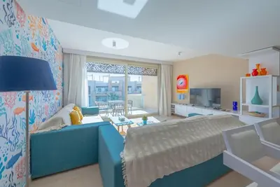a bedroom with a blue bed and a living room at Beach-Inspired 1BR in Mangroovy, El Gouna. Sea & Pool in Hurghada