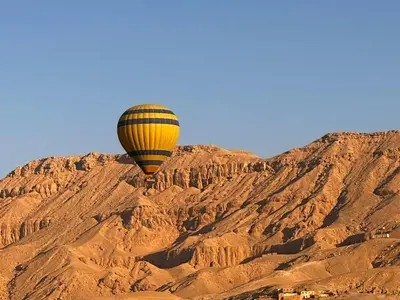 a hot air balloon flying over a mountain at Quiet Gate Guest House in Al Aqālitah