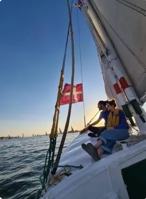 two people sitting on a sail boat in the water at Quiet Gate Guest House in Al Aqālitah
