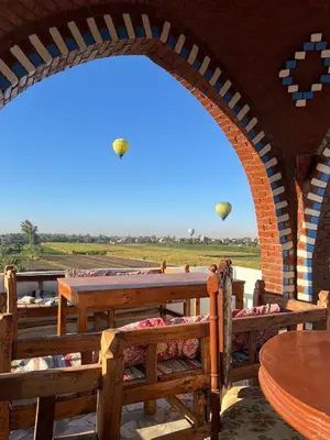 a patio with tables and chairs and kites in the sky at Quiet Gate Guest House in Al Aqālitah