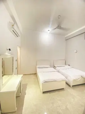 a white room with two beds and a mirror at Quiet Gate Guest House in Al Aqālitah
