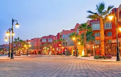 a city street with palm trees and buildings at night at Sheraton Plaza Near Marina in Hurghada