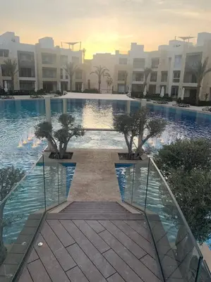 a large swimming pool with trees in front of a building at Mangroovy - 1BR Shiny Ground Floor in Hurghada
