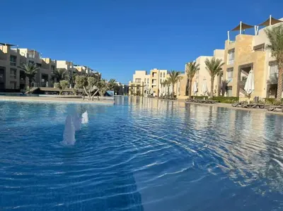 a large pool of water with buildings and palm trees at Mangroovy - 1BR Shiny Ground Floor in Hurghada