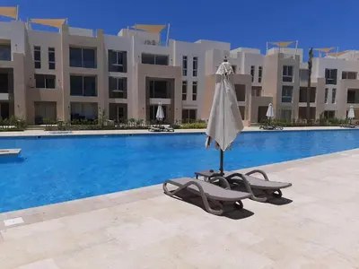 a chair and an umbrella next to a swimming pool at Warm 1BR with @ Mangroovy, El-Gouna M1-7B in Hurghada