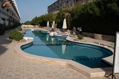 a large swimming pool with people sitting in chairs around it at Fox Beach Stay in Hurghada