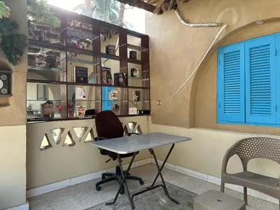 a table and chairs in a room with a wall with shelves at Villa Rebecca Professor's paradise in Luxor
