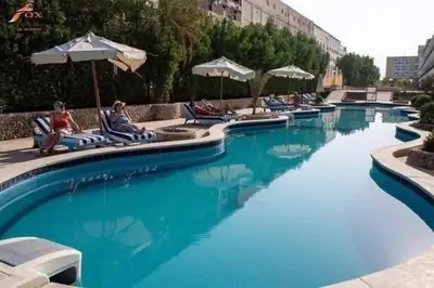 a large swimming pool with chairs and umbrellas at Fox House Resort Apartment in Hurghada