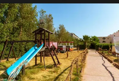 a playground with a blue slide in a park at Fox House Resort Apartment in Hurghada