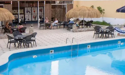 a swimming pool with chairs and tables and umbrellas at Fox House Resort Apartment in Hurghada