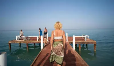 a woman sitting on a pier in the water at Fox house resort Apartment hotel in Hurghada