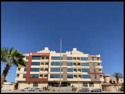 a large building with a palm tree in front of it at Casablanca star Beach Hurghada كازابلانكا ستار بيتش الغردقة in Hurghada
