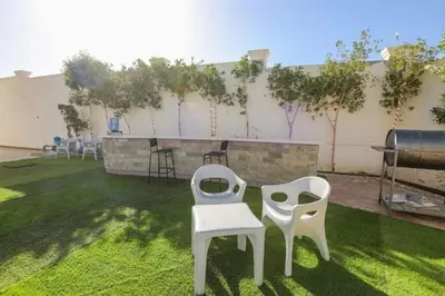 two white chairs sitting on the grass in a backyard at La bonita studio b1 in Hurghada