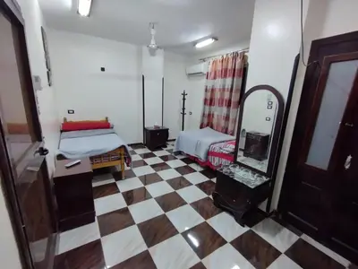 a room with a bed and a mirror and a checkered floor at Couple's Cove in Luxor