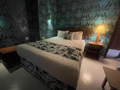 a bedroom with a large bed and a lamp on a table at Golden Sun Hotel - Hurghada in Hurghada
