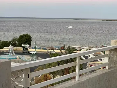 a white fence with a view of the water and a boat at Divers Home Safaga in Safaga