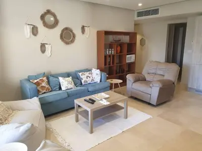 a living room with a blue couch and a table at Mangroovy - 2BR Prodigious Ground Pool & Sea view in Hurghada