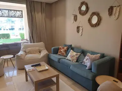 a living room with a blue couch and a table at Mangroovy - 2BR Prodigious Ground Pool & Sea view in Hurghada