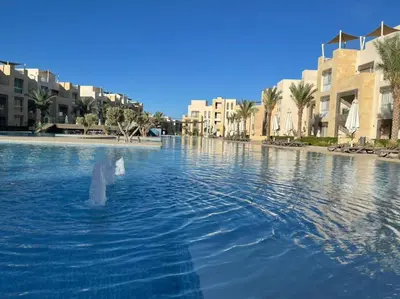 a swimming pool in a resort with palm trees and buildings at Mangroovy- 1BR Sea Breeze Back Sea view in Hurghada