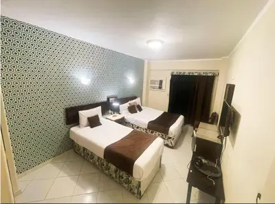 a hotel room with two beds and a television at فندق جولدن صن العروسه طريق الشيراتون السقالة ميدان محافظة البحر الأحمر 84511 مصر in Hurghada