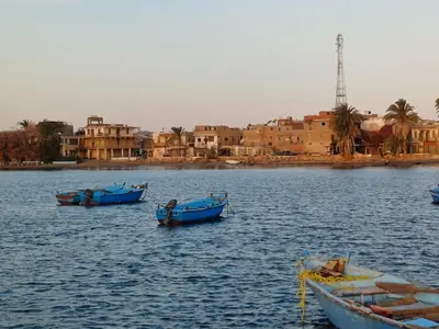 three boats in a body of water with buildings at New Villa Carimo in Quseir