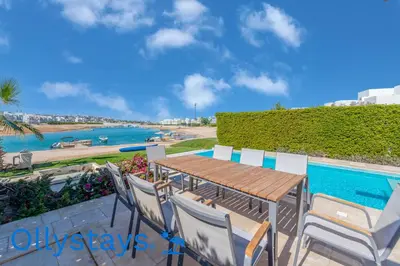 a table and chairs with a view of the water at Ollystays Joubal Lagoon 4 BR Villa Heated Pool in Hurghada
