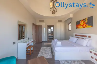 a bedroom with a large white bed and a table at Ollystays Ancient Sands 4 BR Villa Heated Pool in Hurghada