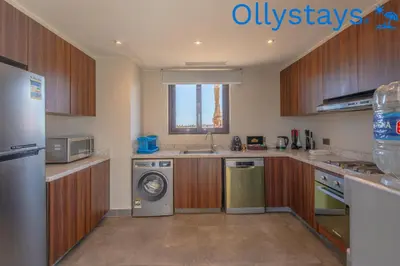 a kitchen with wooden cabinets and a washer and dryer at Ollystays Ancient Sands 4 BR Villa Heated Pool in Hurghada