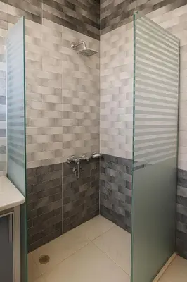 a shower with a glass door in a bathroom at Villa Desert Rose in Luxor