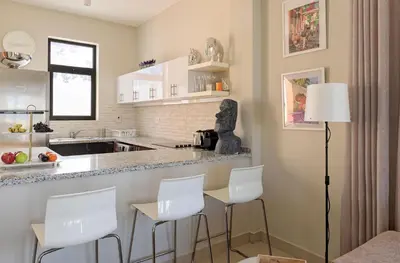 a kitchen with white stools and a counter at Vesta - El Gouna Residence in Hurghada
