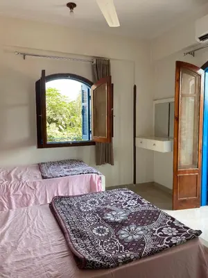 a bedroom with two beds and a window at Gîte Hôtel Ramla Louxor 2 in Luxor