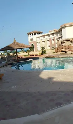 a swimming pool with an umbrella and a building at Royal beach resort in Hurghada