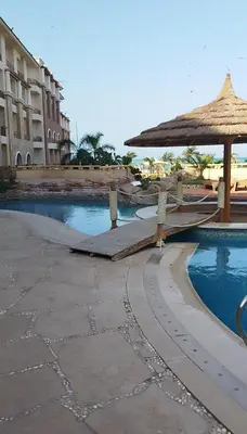 a resort with a pool with a umbrella and a building at Royal beach resort in Hurghada