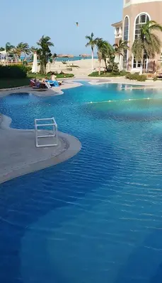 a pool of blue water next to a beach at Royal beach resort in Hurghada