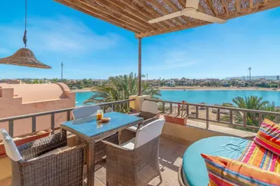 a balcony with a table and chairs and a view of the water at Soulful 1BR in Italian Compound / Nubia, El Gouna in Hurghada