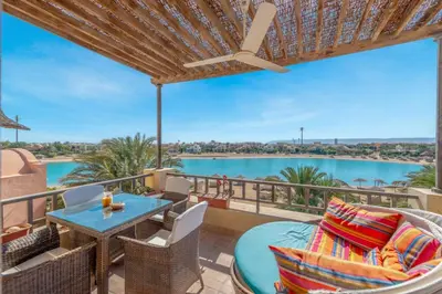 a patio with a table and chairs and a view of the water at Soulful 1BR in Italian Compound / Nubia, El Gouna in Hurghada