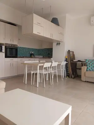 a kitchen with white cabinets and white tables and chairs at Relaxing open Seaview Apartment in Hurghada